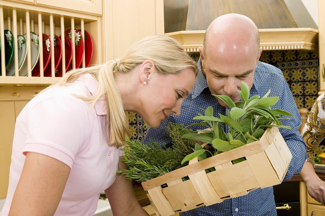 Couple examining fresh herbs in kitchen