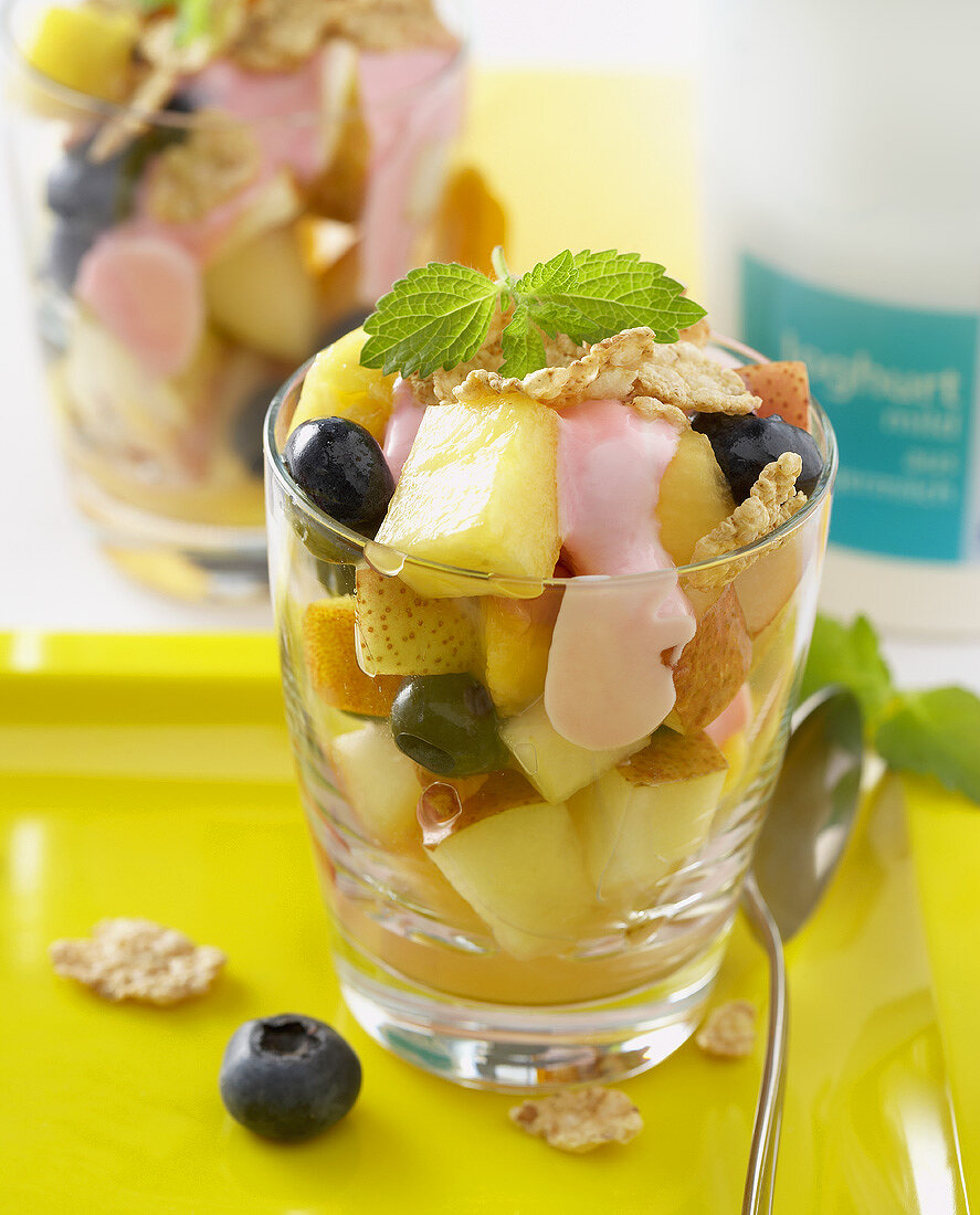 Fruit salad with berry yoghurt and cereal flakes in glass