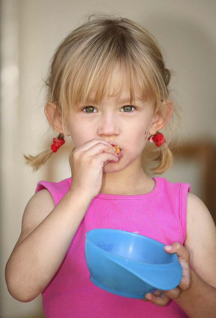 Mädchen isst Kartoffelchips aus einer blauen Schale