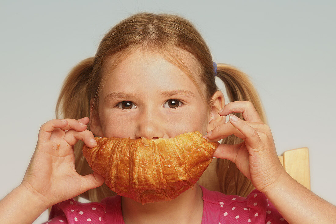 Mädchen isst Croissant