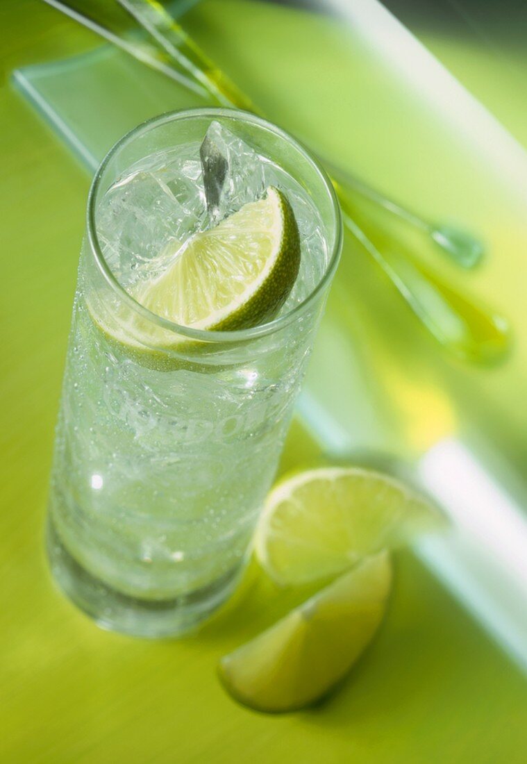 A glass of mineral water with ice cubes and lime