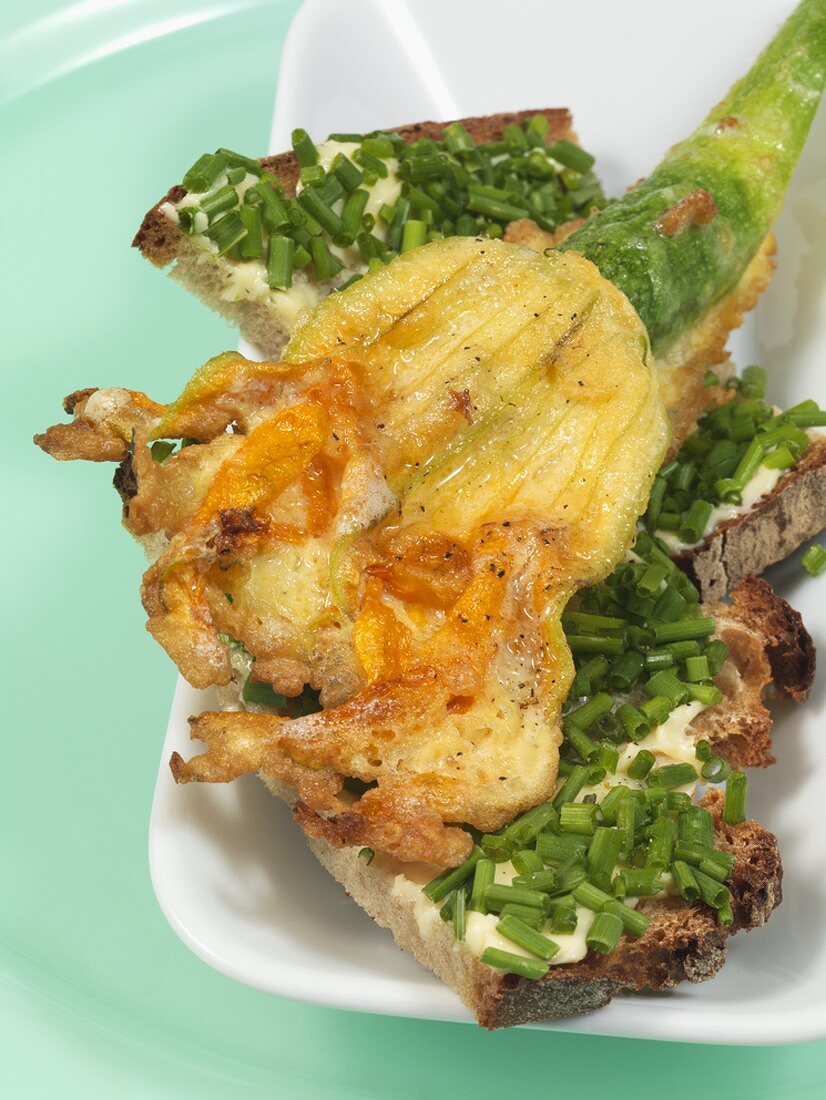 Deep-fried courgette flower on bread & butter with chives