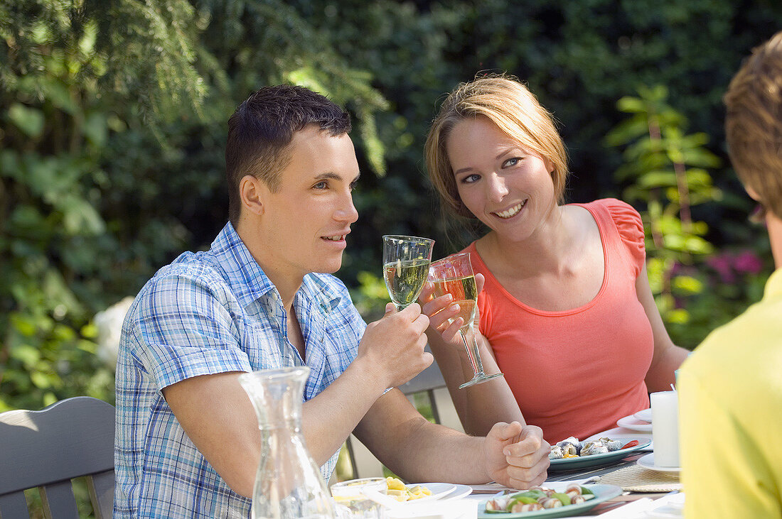Junges Paar trinkt Weißwein am Tisch im Freien