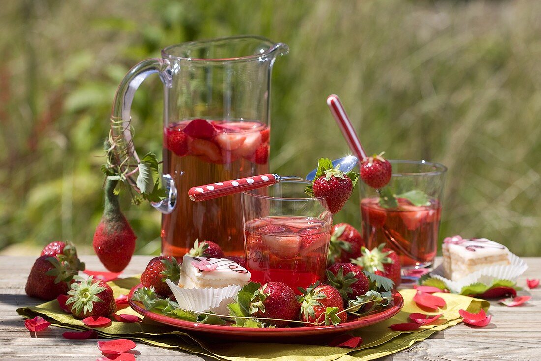 Erdbeerbowle, frische Erdbeeren & Petit Fours auf Gartentisch