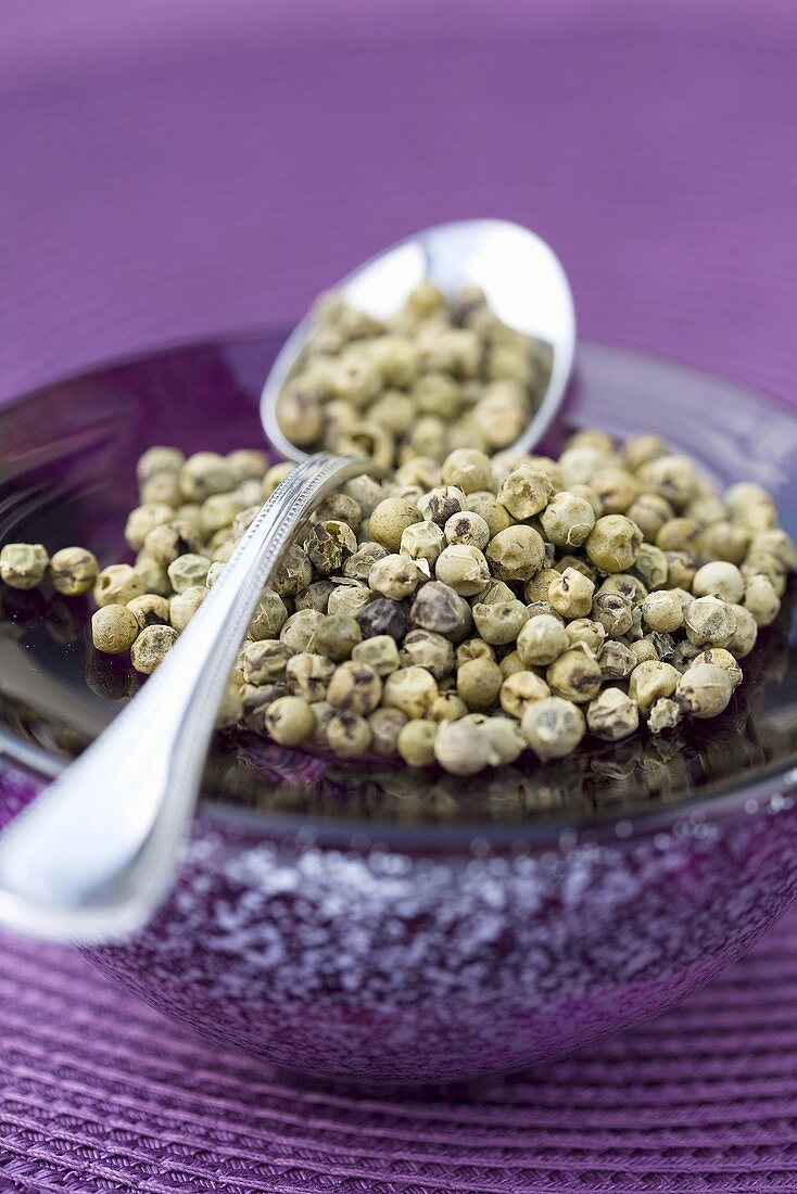 Green peppercorns on spoon and plate