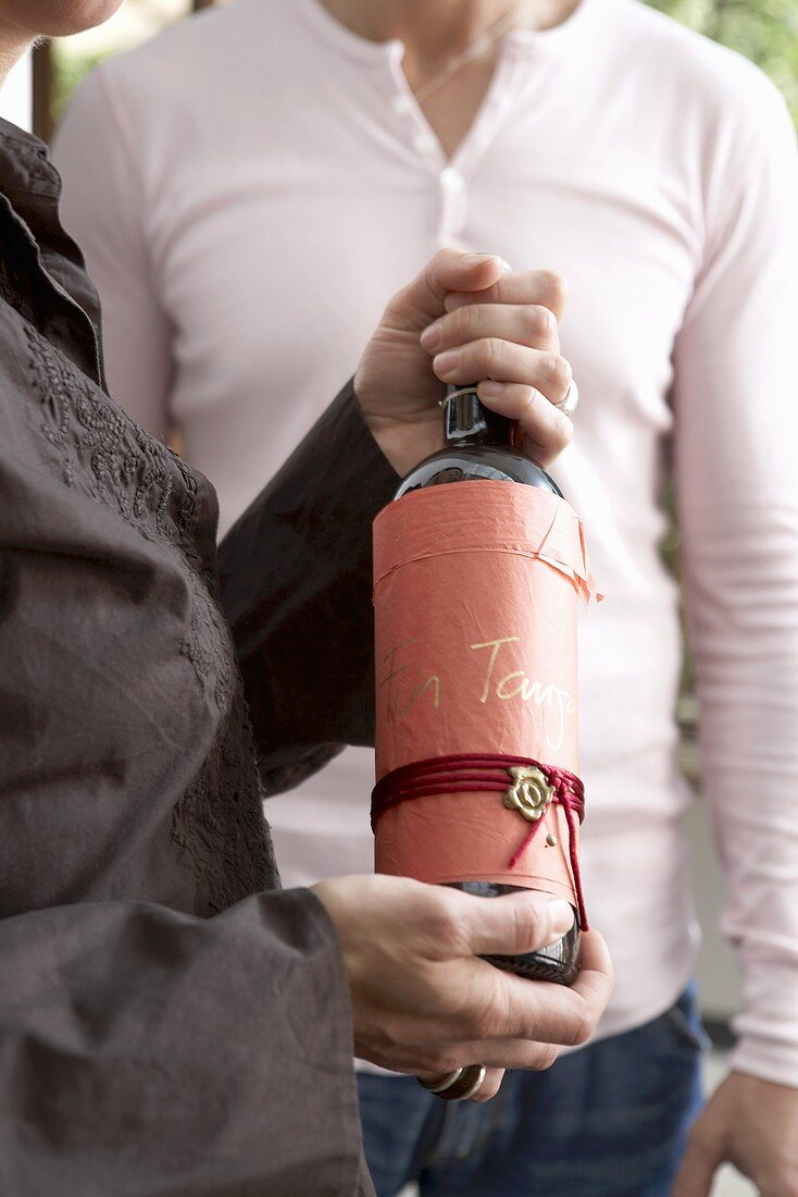 Woman holding a gift-wrapped wine bottle in her hands