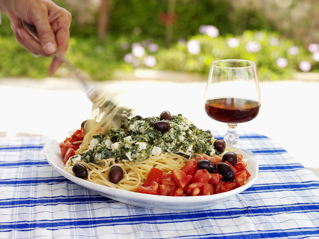 Spaghetti mit Spinat und Feta, garniert mit Tomatensalat