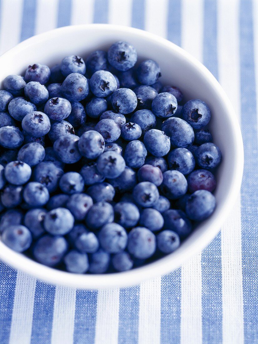 Bowl of fresh blueberries on striped cloth