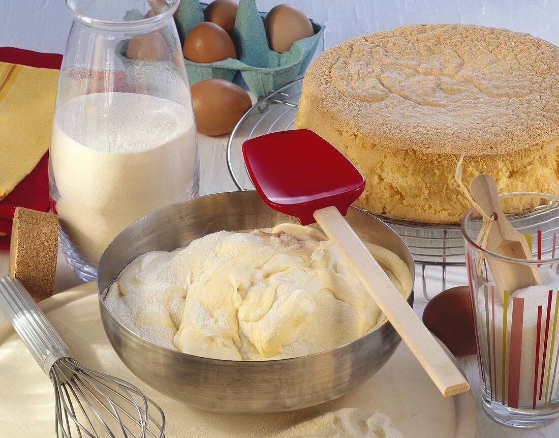 Yeast dough in mixing bowl, spatula, sponge cake, flour