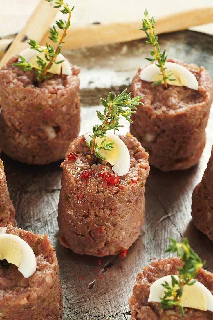 Steak tartare appetisers with boiled egg and thyme