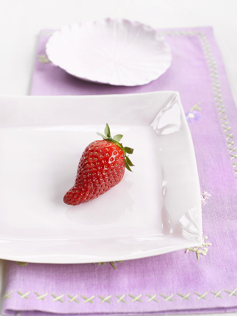 Eine Erdbeere auf weißem Porzellanteller