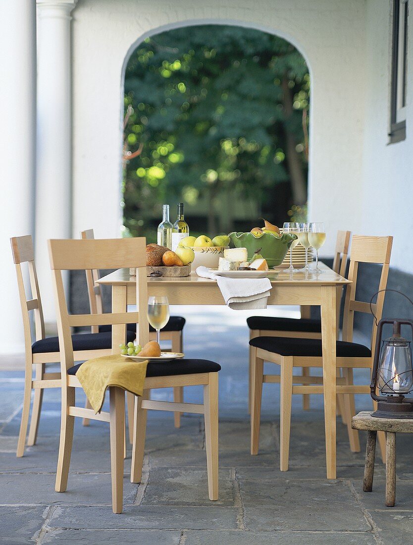 Tisch mit Käse, Früchten und Weißwein auf der Terrasse