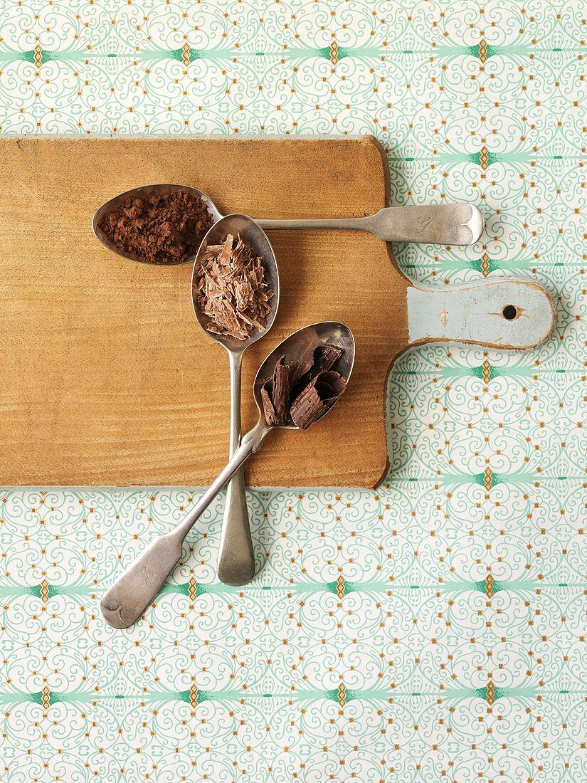 3 spoons with cocoa powder, grated chocolate & chocolate curls