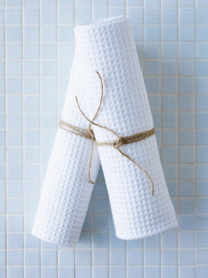 Rolled-up towels on pale blue tiles