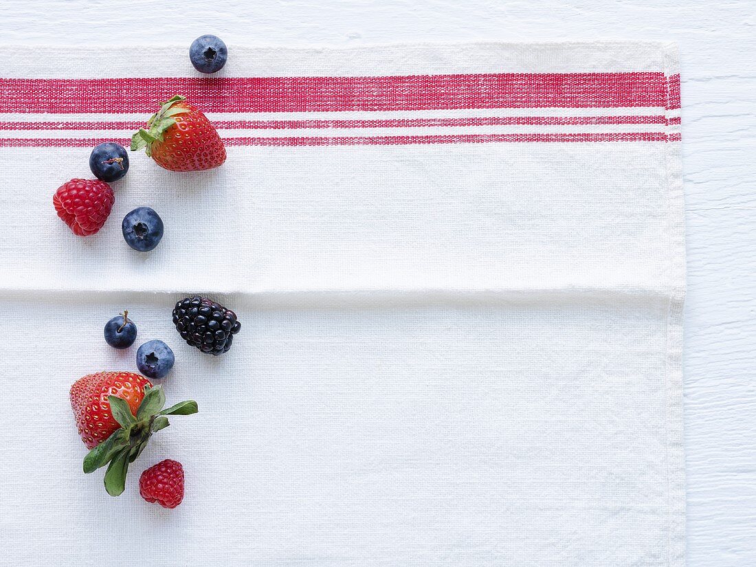 Strawberries, blueberries and blackberries on tea towel