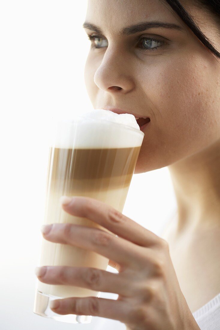 Junge Frau trinkt Latte Macchiato