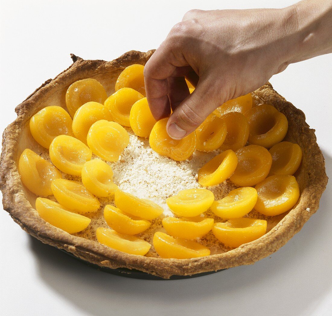 Filling a puff pastry tart case with apricots