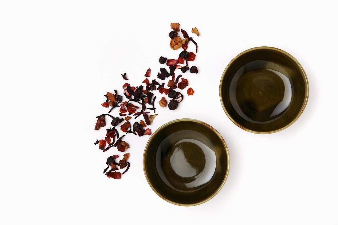 Getrocknete Teeblätter und zwei Teeschalen