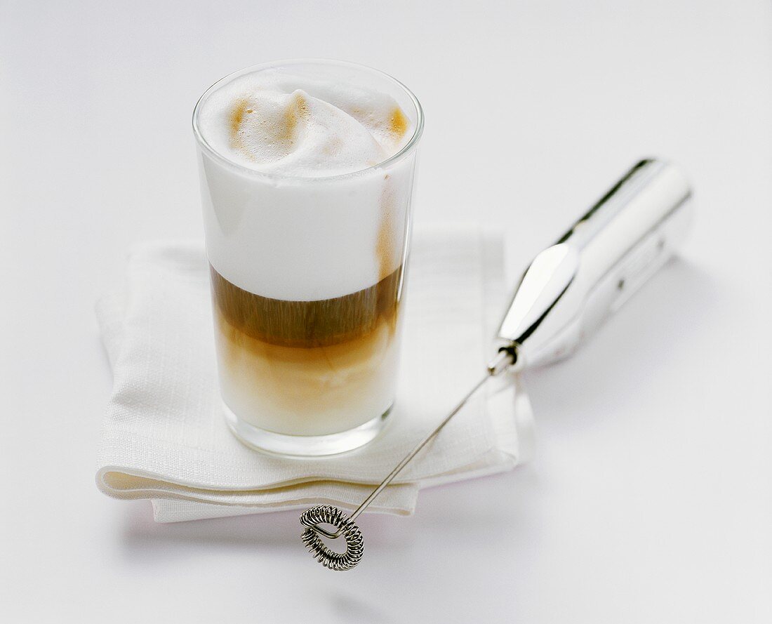 Latte macchiato, mini-whisk beside it