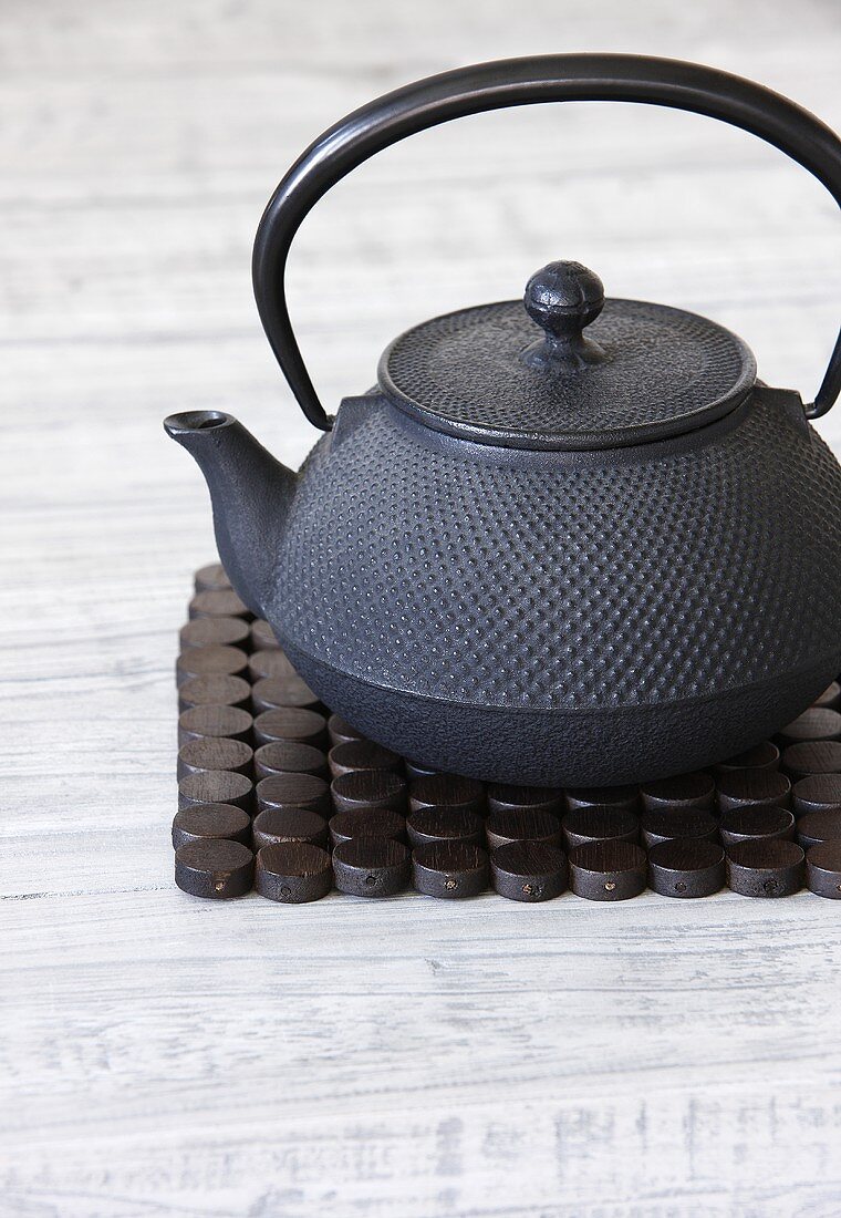 Asiatische Teekanne aus Gusseisen auf Holzset