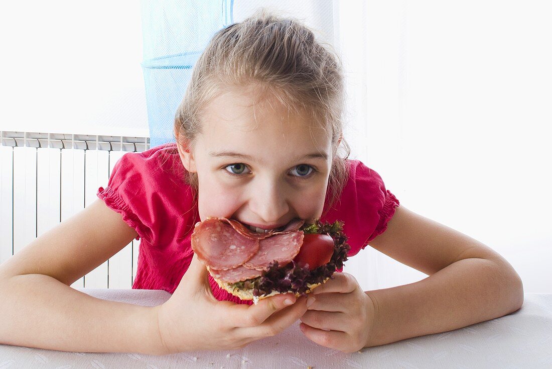 Girl eating an open ham sandwich