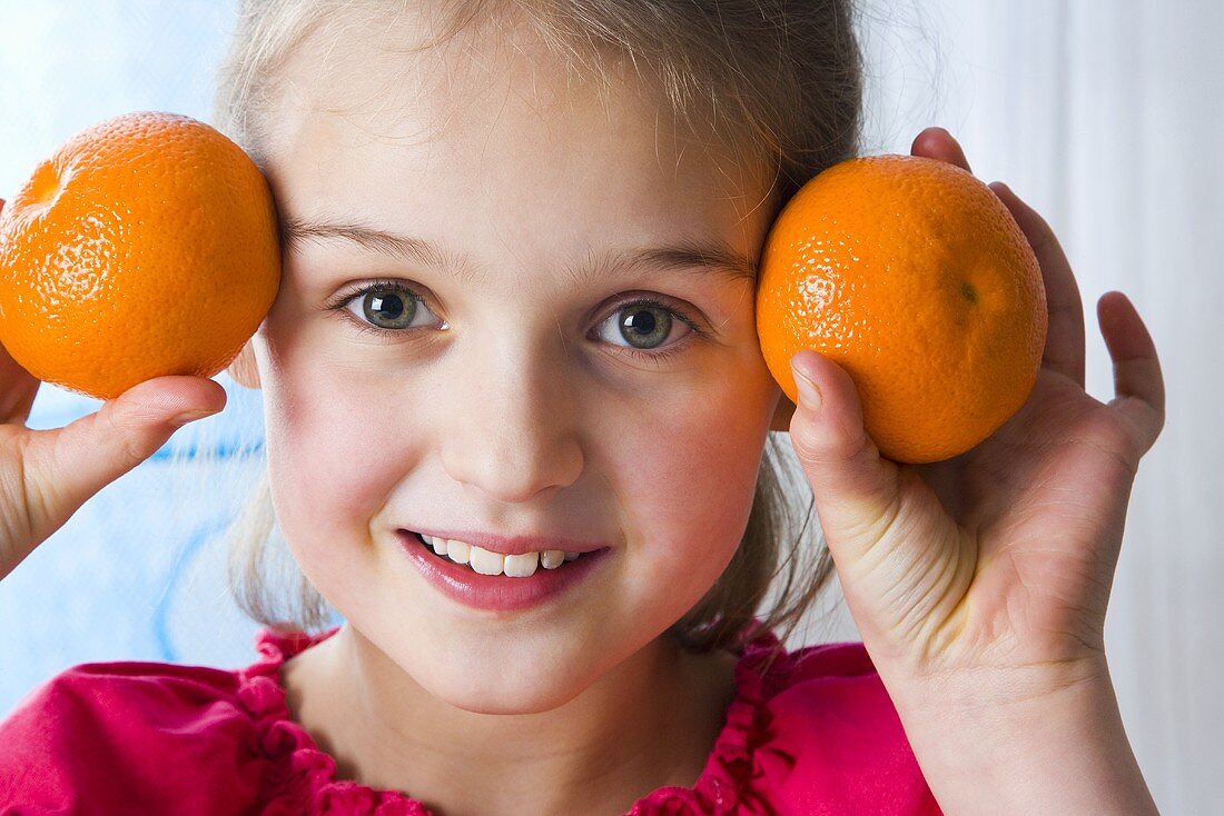 Girl holding two mandarin oranges