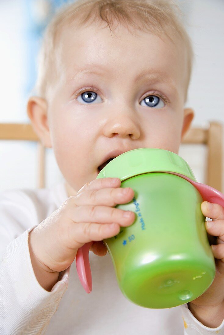 Small child drinking out of a training cup