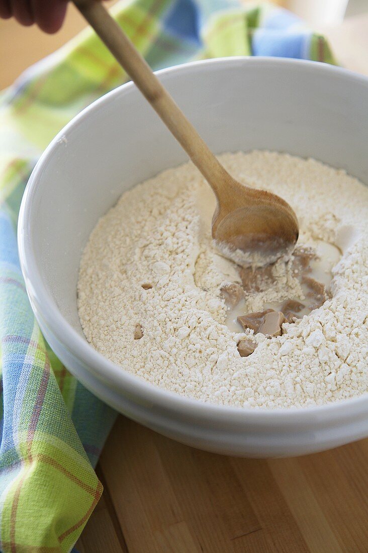 Flour with yeast and milk in a bowl