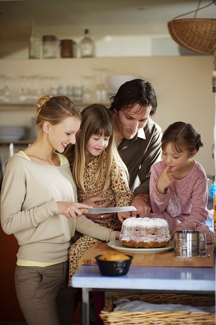 Junge Familie beim Kuchen aufschneiden