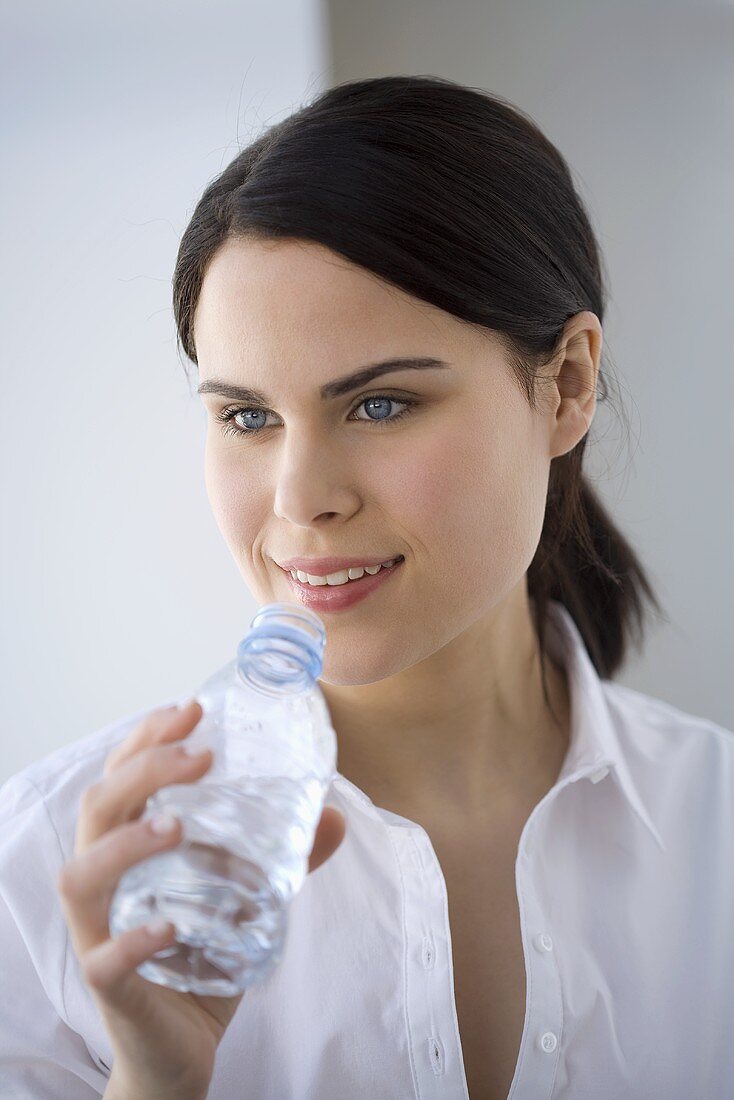 Junge Frau trinkt Mineralwasser aus der Flasche