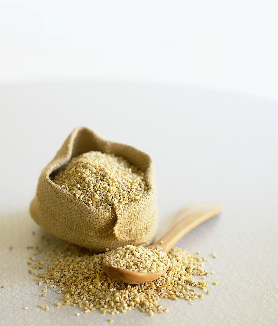 Kibbled oats on wooden spoon and in small sack