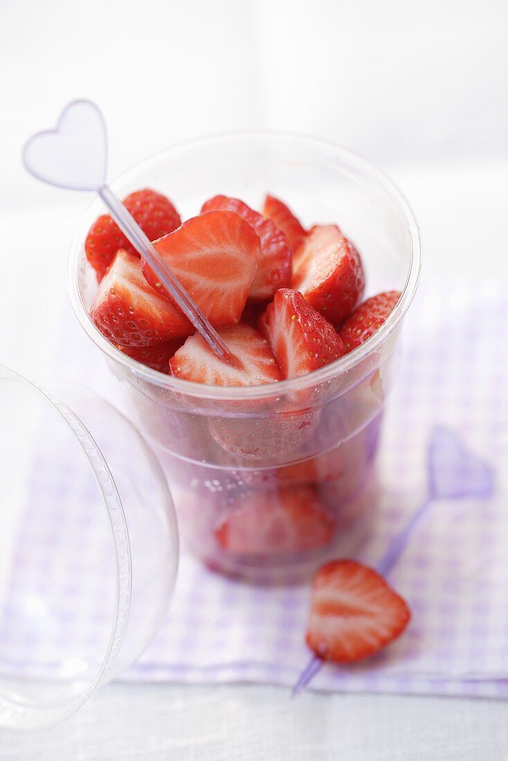 Fresh strawberries with cocktail stick in a plastic tub