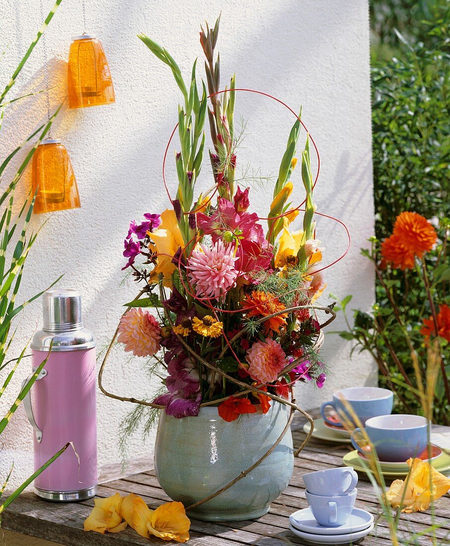 Arrangement of gladioli & dahlias on table laid for coffee