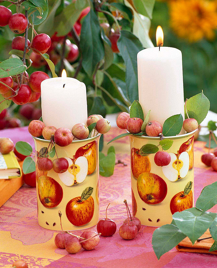 Mit Zieräpfeln gefüllte Tassen als Kerzenhalter