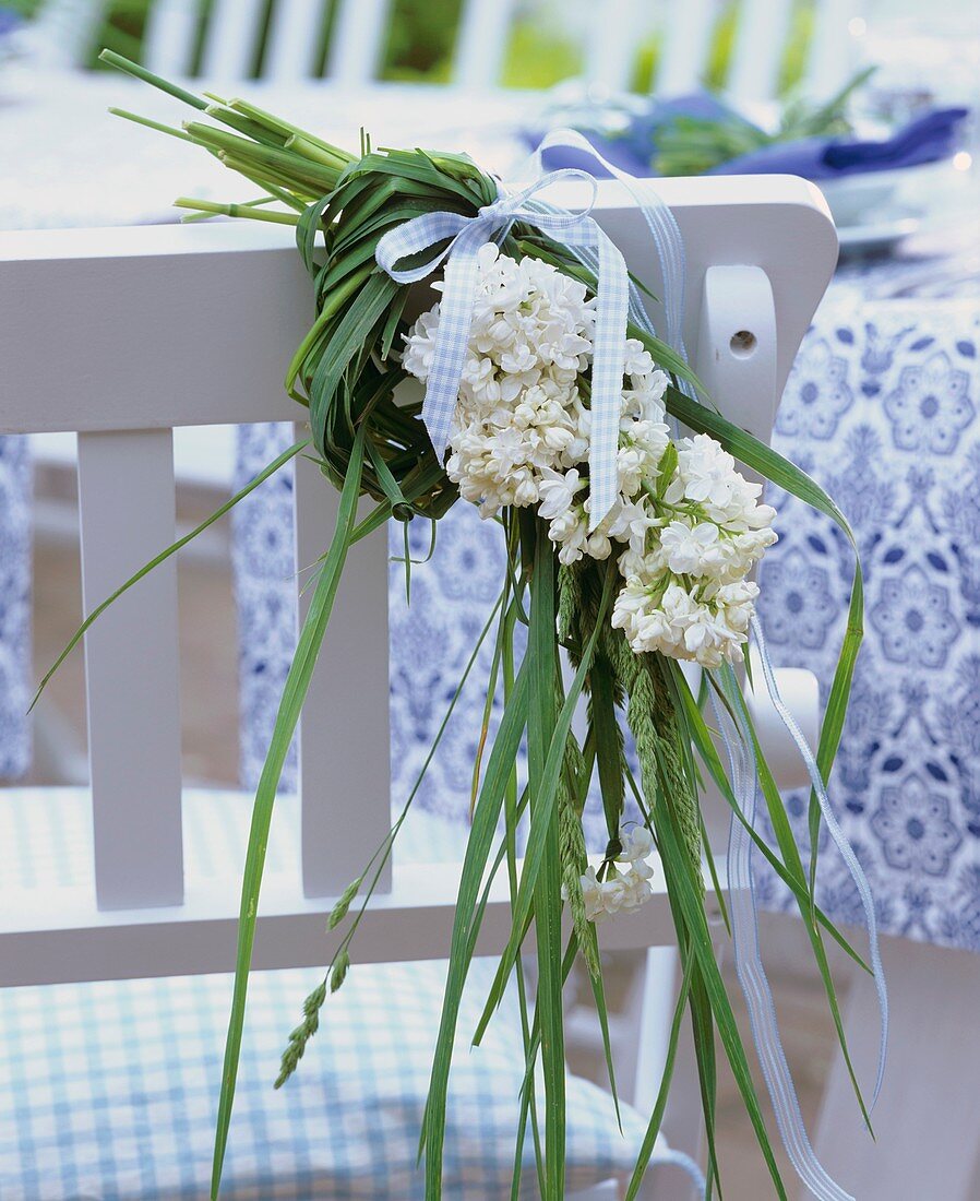 White lilac and grasses on the back of a chair