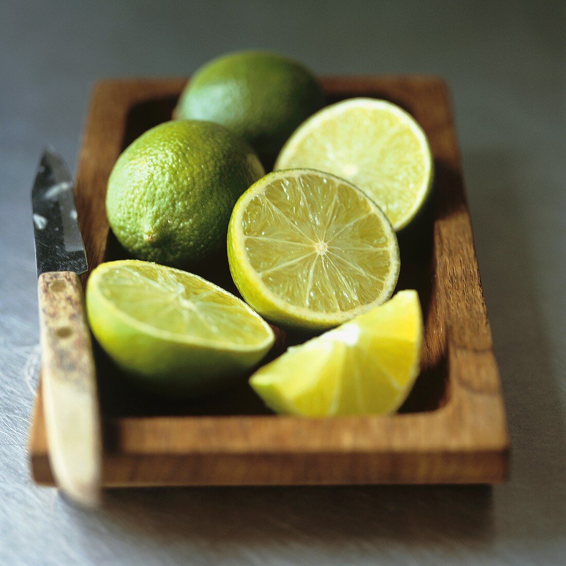 Limes with knife in a wooden dish