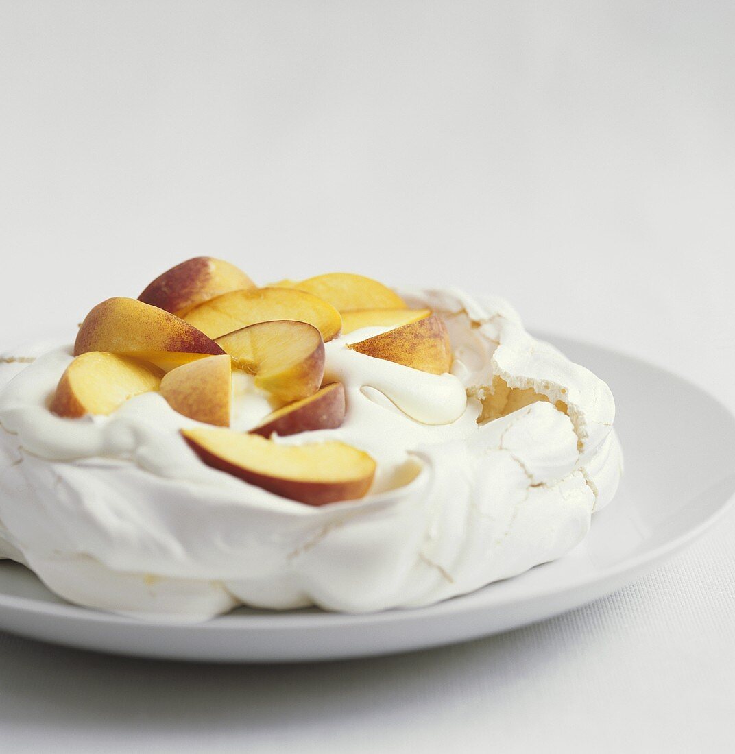 Pavlova with peach slices and cream