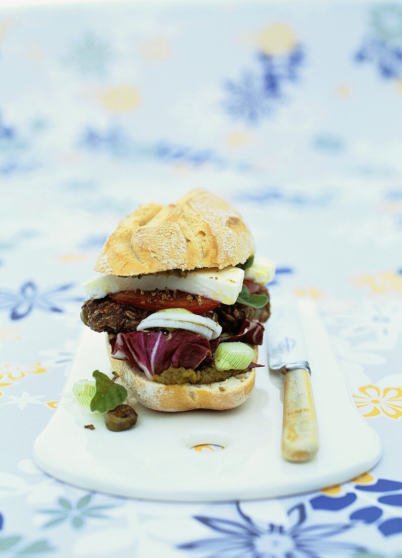 Grain and olive burger in bun with pesto and feta cheese