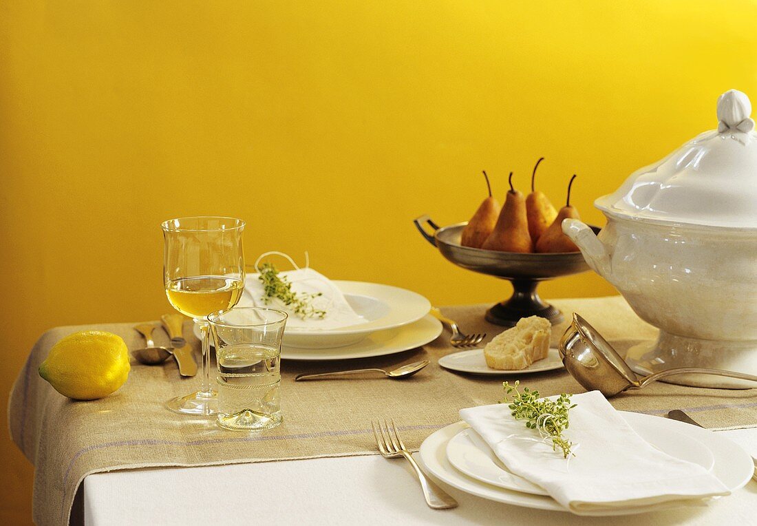 Laid table with soup tureen and fresh pears