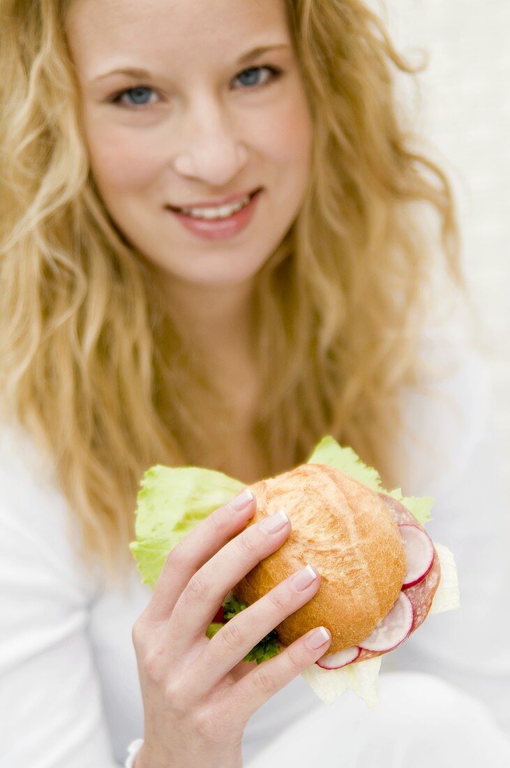 Young woman eating a filled roll