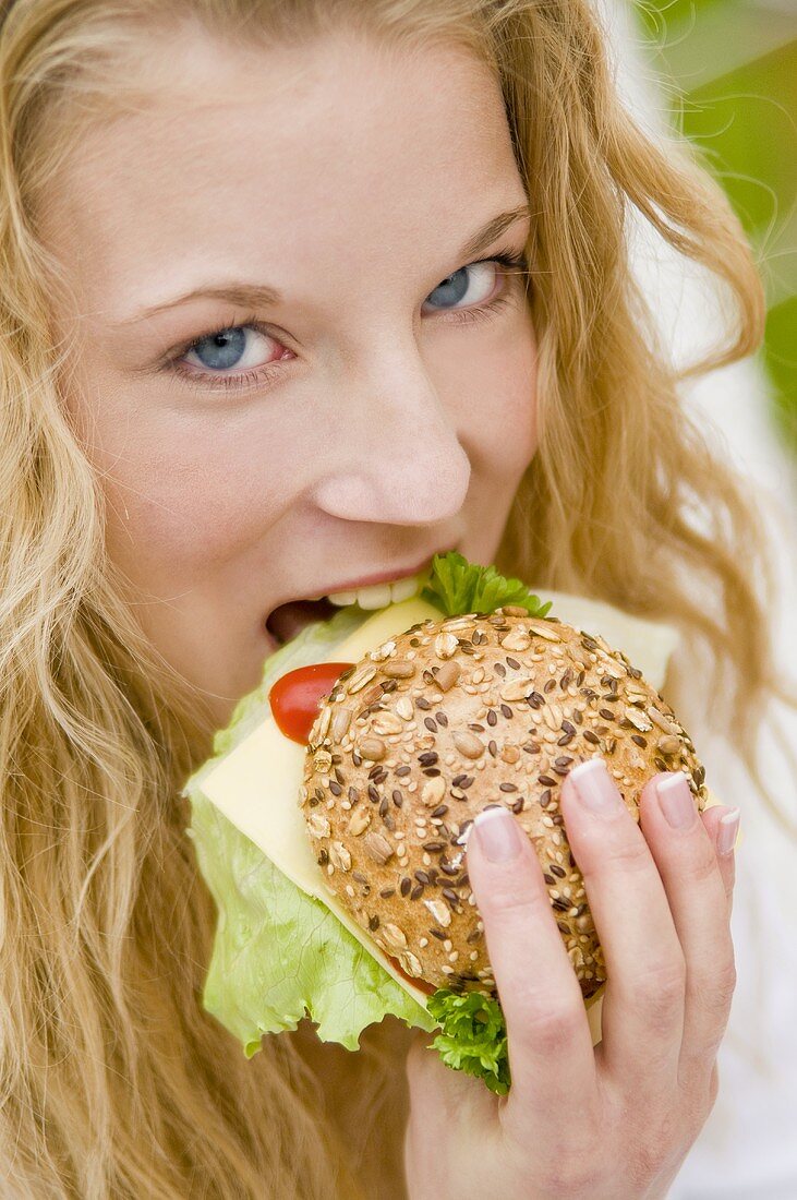 Young woman eating a filled mixed seed roll