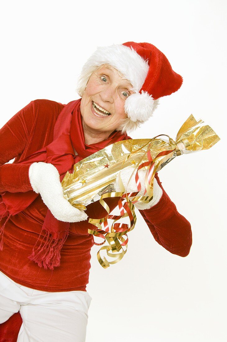 Elderly lady in Father Christmas hat holding a gift
