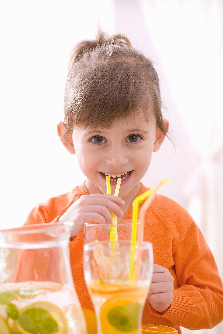 Little girl drinking lemonade through a straw
