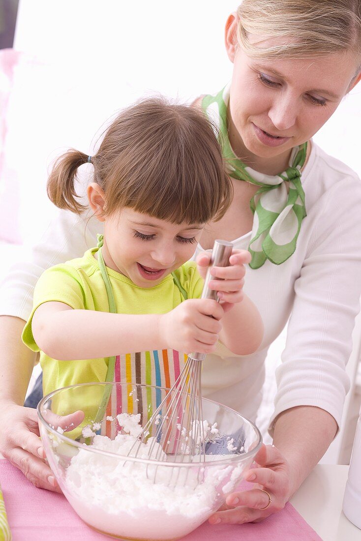 Mother and daughter whisking egg whites