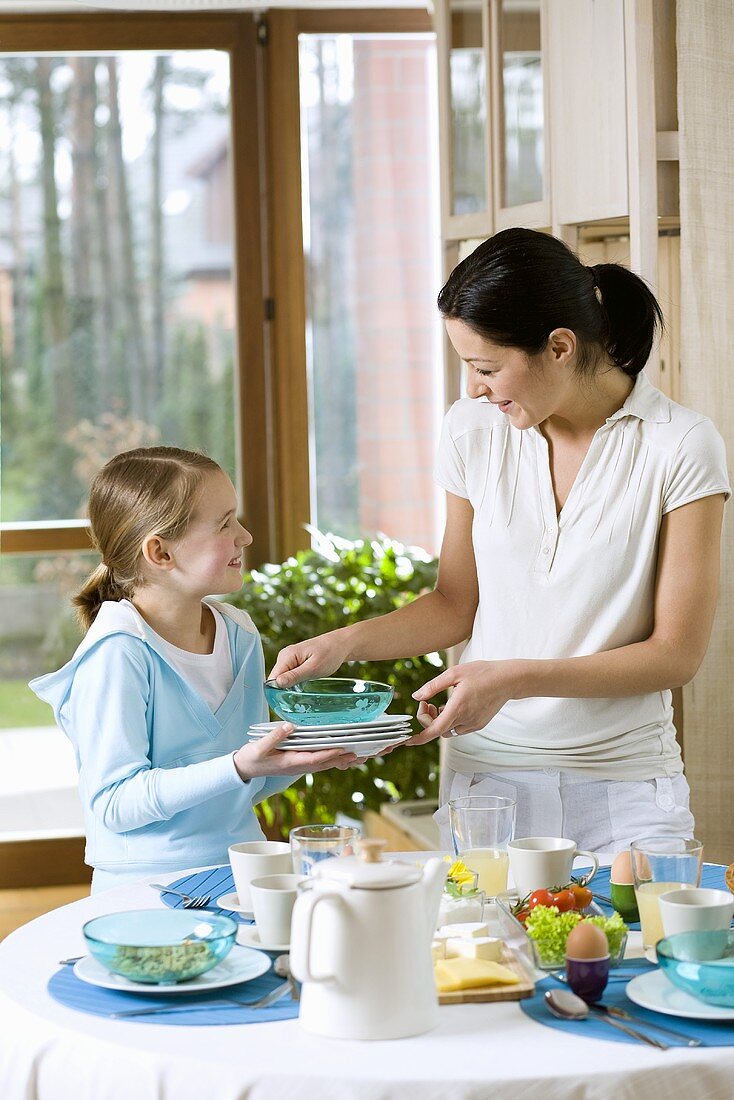 Mutter und Tochter decken den Früchstückstisch