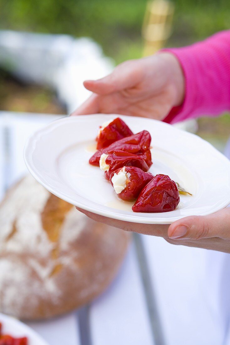 Woman serving red peppers stuffed with feta