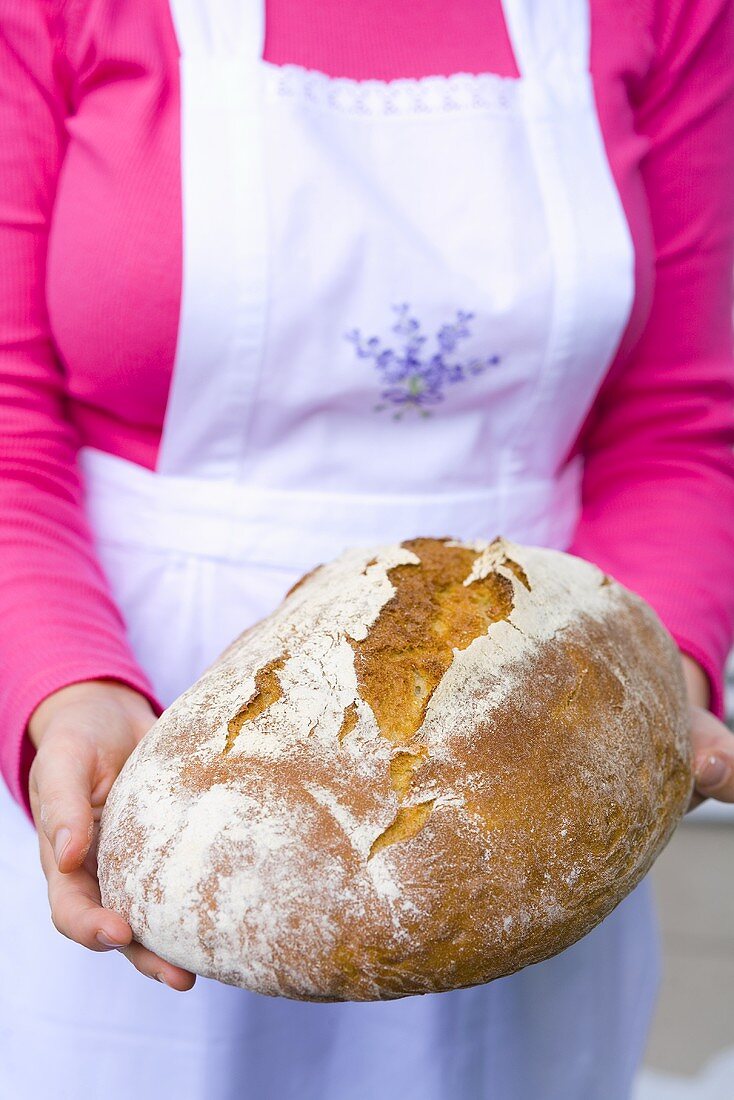 Frau hält selbst gebackenes Brot