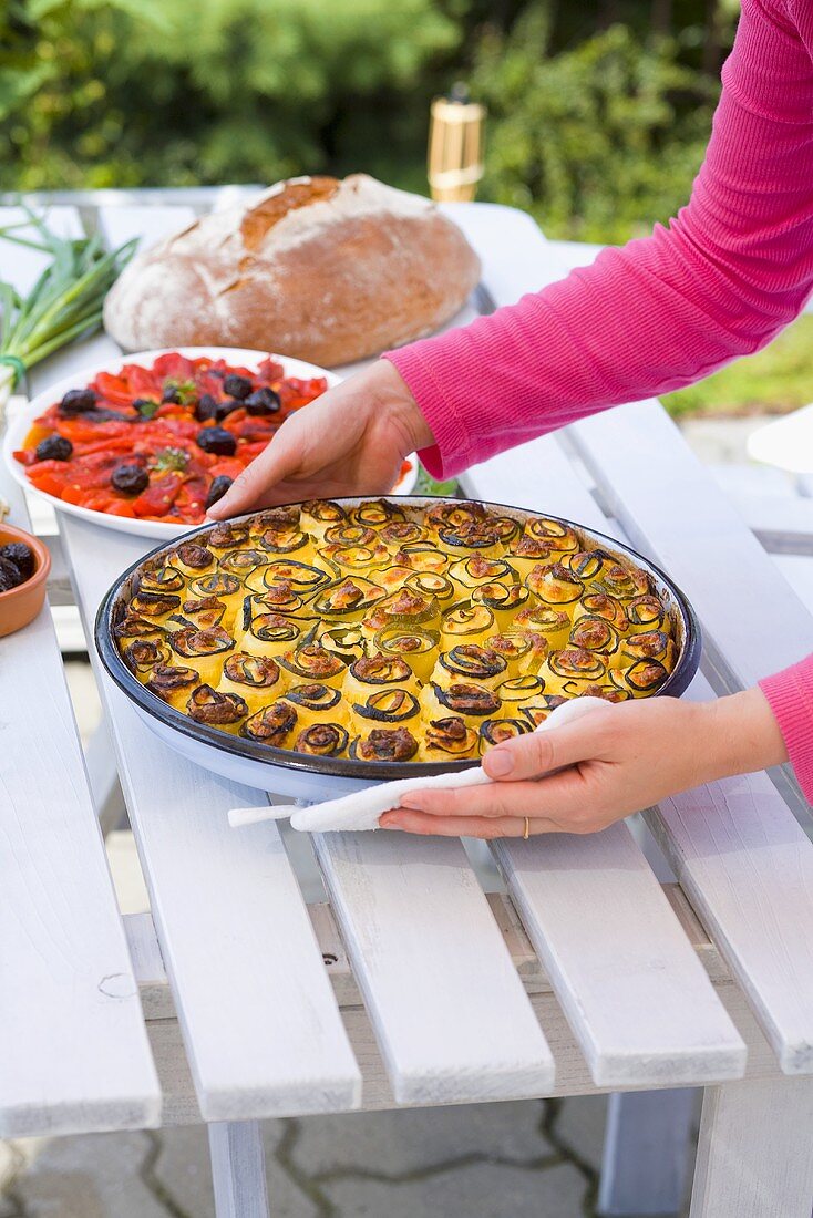 Woman putting courgette bake on table out of doors