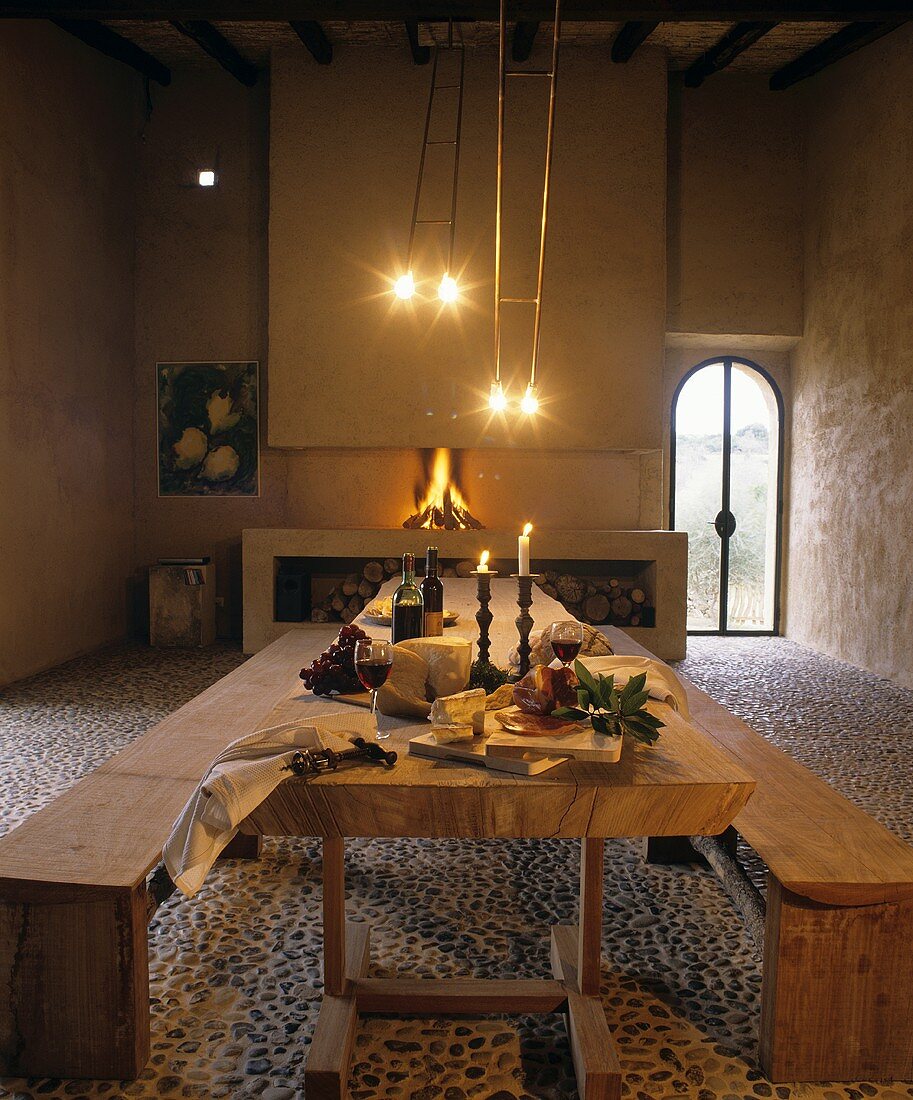 Esstisch mit Schinken, Käse & Rotwein, im Hintergrund Kamin