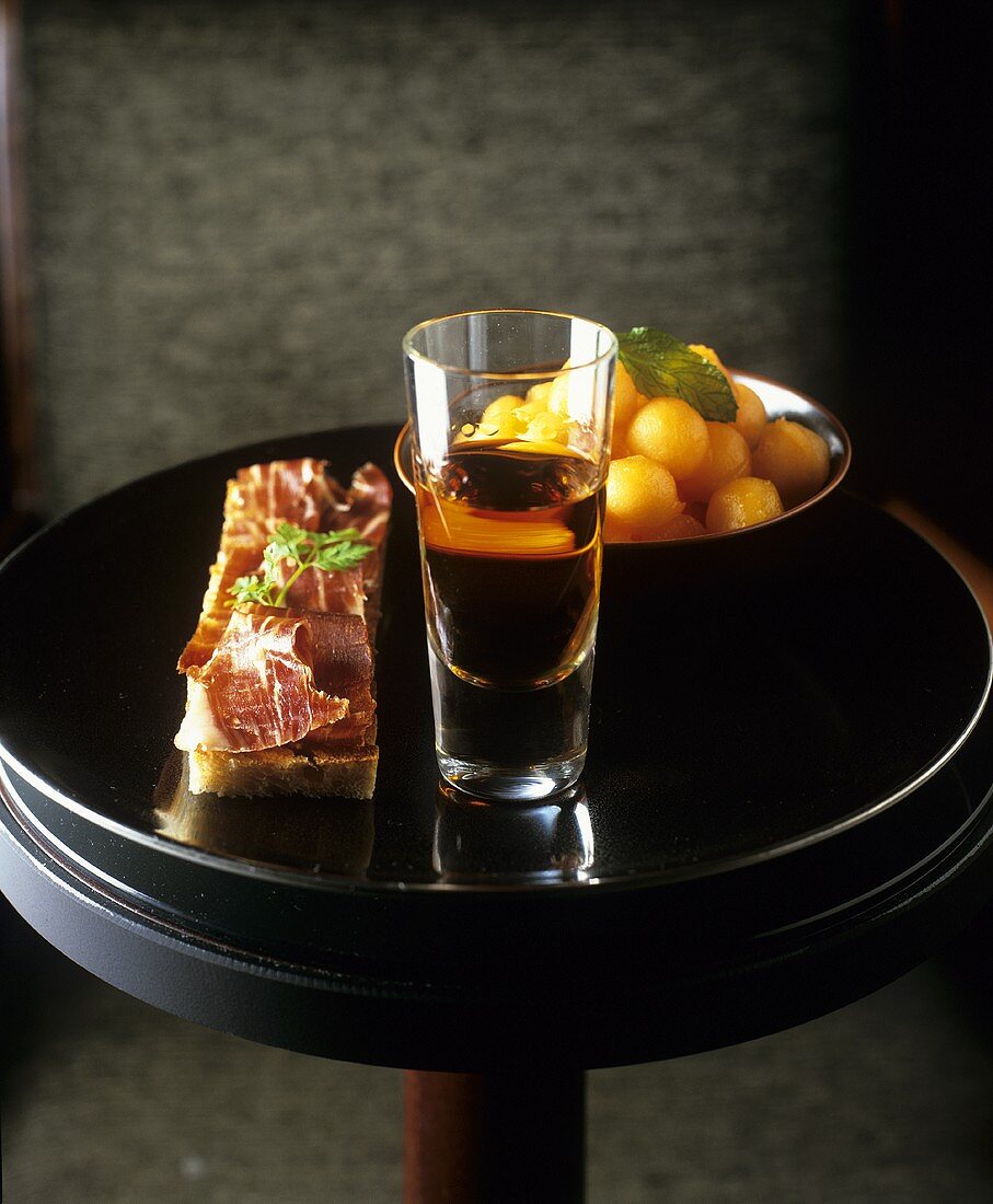 Spanish appetisers: ham on bread, melon balls and sherry